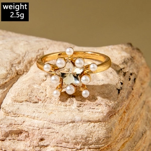 Detailed shot of golden star ring with central crystal and pearls on stone, weighing 2.5g