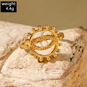 Detailed view of a gold evil eye ring with a pearl inlay on a textured stone surface