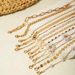 Détails de bracelets dorés avec perles et strass disposés sur un socle en pierre blanche