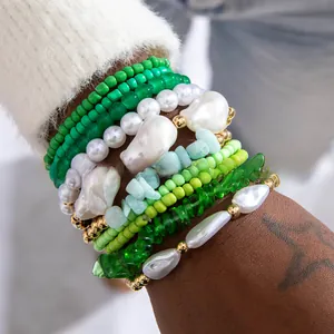Gros plan de bracelets bohèmes à perles vertes superposées et détails dorés