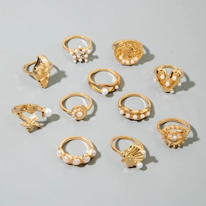 10-piece gold ring set featuring ocean-themed sea shells, stars, and pearls on gray background