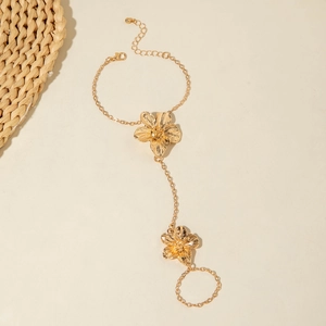 Detailed close-up of golden finger bracelet with large brushed texture flower designs