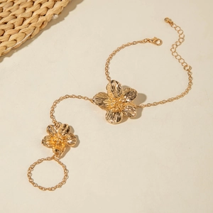 Detail view of golden flower finger bracelet with textured floral design and lobster clasp