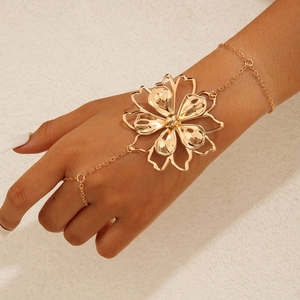 Detail of a golden flower slave bracelet featuring a polished finger ring hand chain