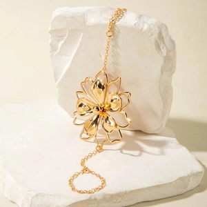 Detailed close-up of a gold hollow floral hand harness displayed on white stone textures
