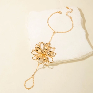 Detail view of a gold flower hand harness jewelry piece on a minimalist stone display