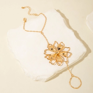 Macro detail of golden flower finger bracelet with intricate hollow petals and wrist chain