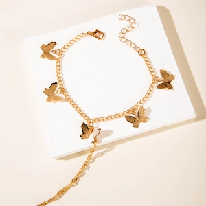 Detailed shot of golden butterfly link bracelet on white stone with sharp shadows
