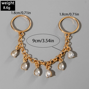 Detail of gold chain body jewelry featuring teardrop crystals and double rings