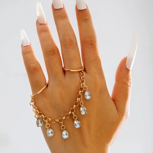 Detail of gold hand chain featuring pear-shaped crystals and double ring connection