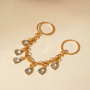 Detail of a gold-plated body chain featuring smooth rings and six teardrop crystal charms