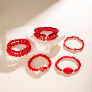 Red beaded bracelet set with heart charms and gold accents on stone display