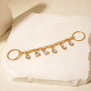 Detail of gold chain with drop-shaped crystals resting on a textured white stone
