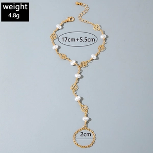 Detail view of gold finger bracelet with hollow rose and white imitation pearls