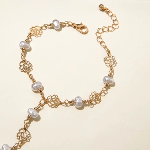 Detailed shot of golden rose charms and pearls on an elegant women's link bracelet