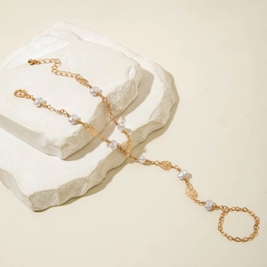 Detailed view of a gold rose and pearl hand harness on elegant stone pedestals