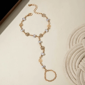 Detail view of a gold finger bracelet featuring hollow roses and elegant white pearls