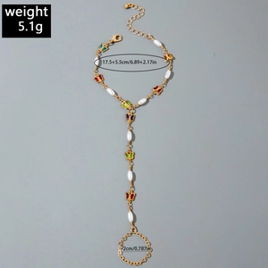 Detail of gold slave bracelet with colorful enamel butterflies and white faux pearls