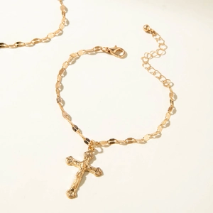 Close-up of gold-plated cross pendant bracelet with adjustable flat link chain clasp