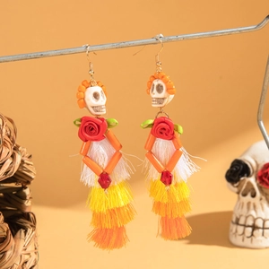 Détail des boucles d'oreilles squelette Jour des Morts avec roses rouges et pompons colorés