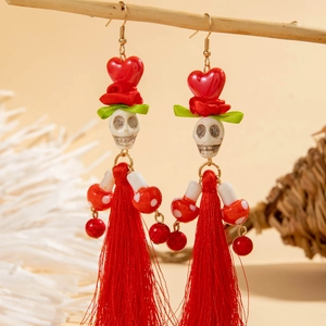 Détail de boucles d'oreilles tête de mort gothiques avec roses rouges et franges