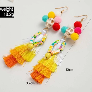 Détail de boucles d'oreilles tête de mort colorées avec pompons et perles perlées