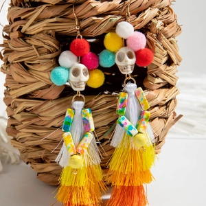 Détail de boucles d'oreilles crâne bohèmes avec pompons colorés et franges à franges
