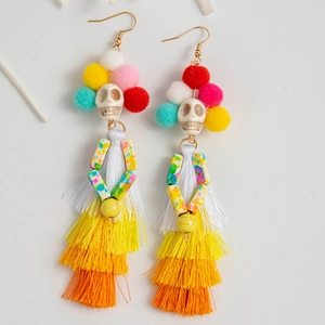 Détail de boucles d'oreilles punk bohème avec tête de mort, pompons et franges colorées