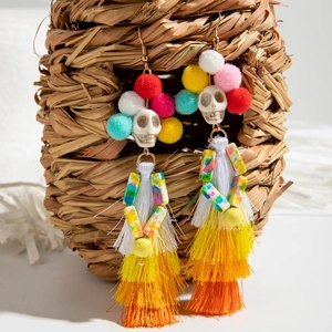 Détail de boucles d'oreilles tête de mort avec pompons colorés et longues franges