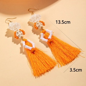 Détail de boucles d'oreilles tête de mort d'Halloween avec fleurs en dentelle et pompons