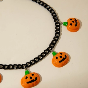 Close-up of black chain choker with three orange pumpkin pendants for Halloween style