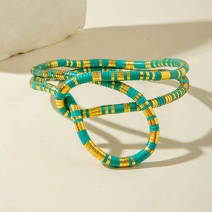 Detail of bohemian snake-like necklace with blue and gold Heishi beads on white rock