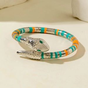 Detail of snake bracelet showing textured scales and green gemstone eyes on stone base