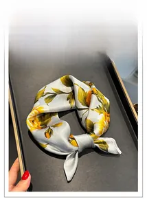 Macro shot of silver silk scarf detailing smooth texture and yellow floral patterns