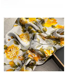 Close-up of luxurious silk scarf with yellow floral print on silver damask satin fabric