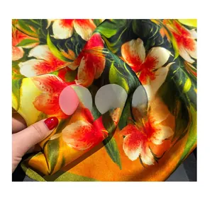Detailed macro view of floral print silk fabric with vibrant lilies and glossy finish