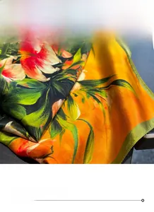 Detailed view of the fine stitched edge on a vibrant orange floral silk scarf for women