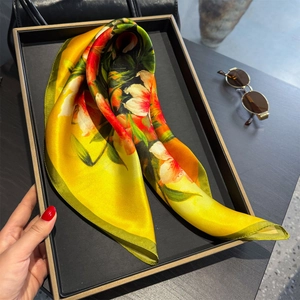 Silk floral square scarf with large yellow and red blossoms on an elegant display tray