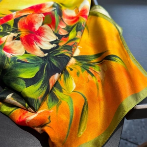 Detailed view of silk scarf with vibrant orange lily print and rolled edges