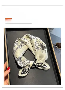 Detail of silk square scarf featuring elegant black floral and vine prints on white fabric