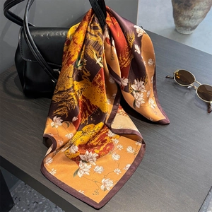Retro silk square scarf with landscape print draped over a black leather handbag