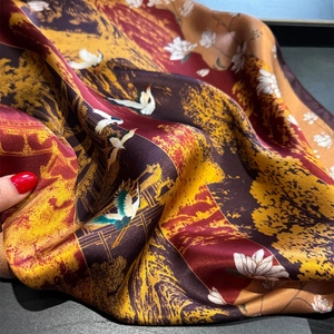 Detailed macro view of silk scarf with crane and lotus print and smooth satin texture