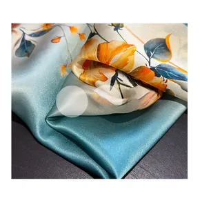 Macro shot of silk scarf fabric showing orange floral patterns and satin texture