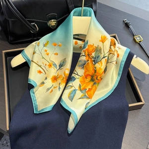 Elegant silk scarf with floral print draped over a dark sweater and stylish accessories