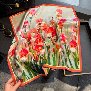 Silk scarf with iris floral print and vibrant orange hem shown with luxury accessories