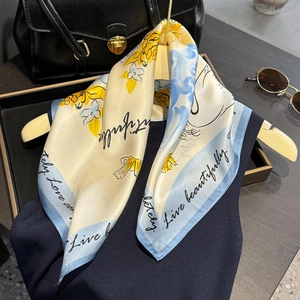 Elegant silk scarf with floral bird print and 'Live beautifully' text in creamy white