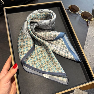 Carré de soie de mûrier 53cm avec motifs floraux bleus sur un plateau de présentation