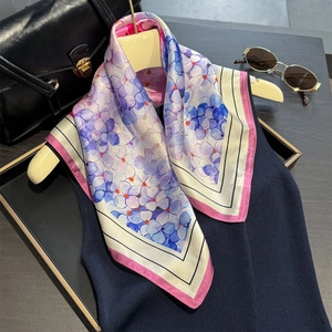 Silk scarf with blue hydrangea pattern and pink borders on a navy sweater backdrop