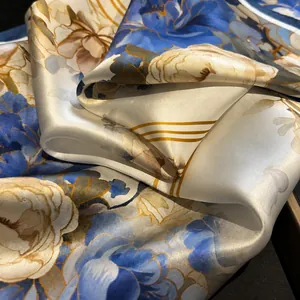 Close-up of elegant silk scarf showing satin texture and floral pattern with a soft drape
