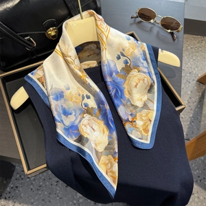 Elegant ivory silk scarf with yellow and blue floral prints on a beige hanger